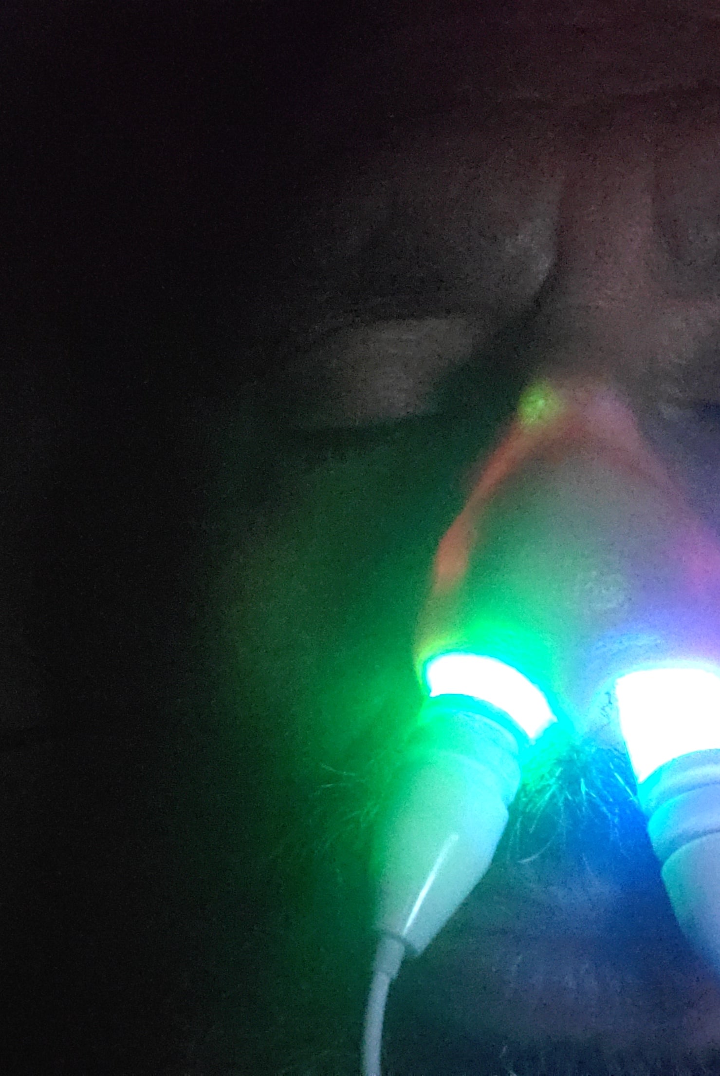 Man with a beard using the green and blue colored Nose Light Device before bed
